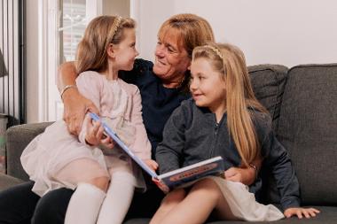 Lesley with young girls reading a book