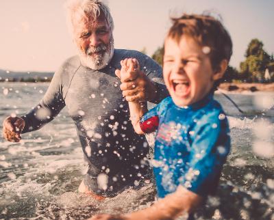 Older man and young boy splashing in the sea allowances